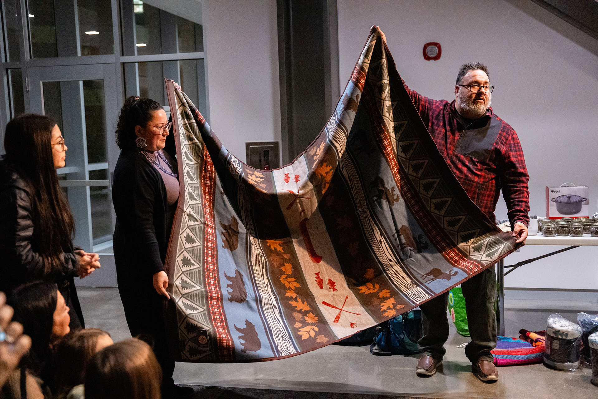 Emily Sorroche and Kevin Leonard present a blanket at poetry event.