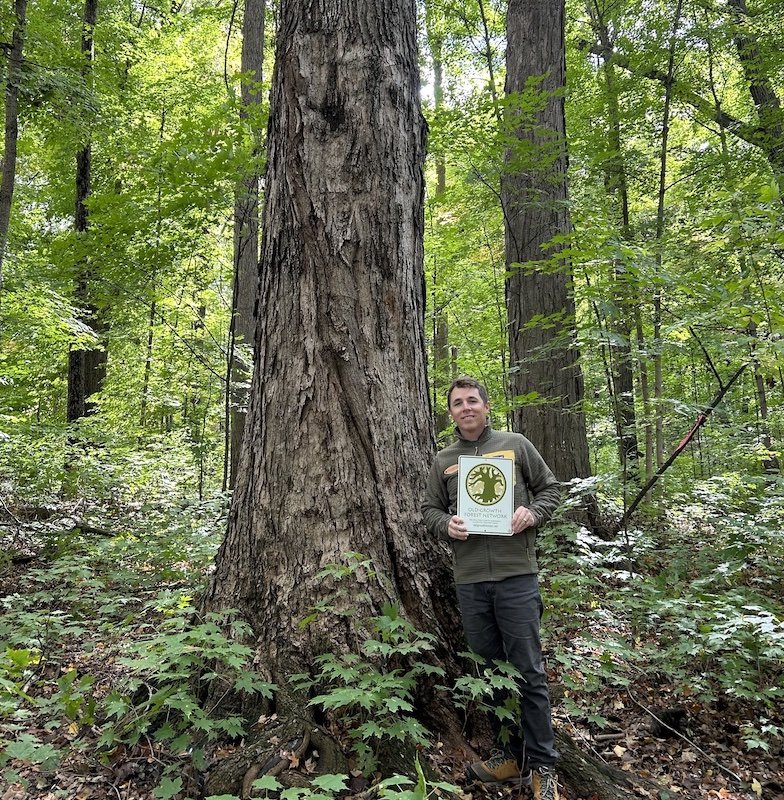 Nick Sanchez in front of a tree at the Baker Woodlot on MSU's campus