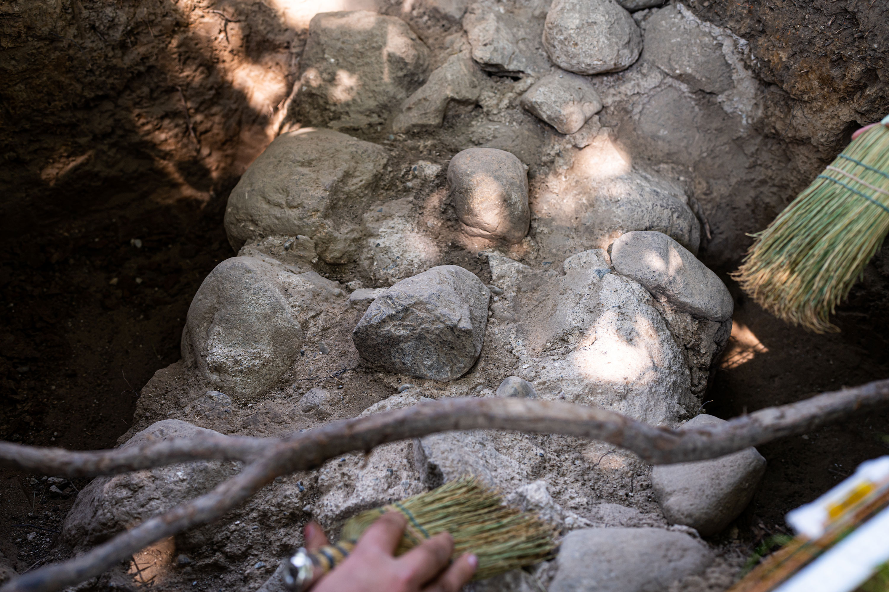 Stones and cement surrounded by dirt. They are being brushed off with brooms.