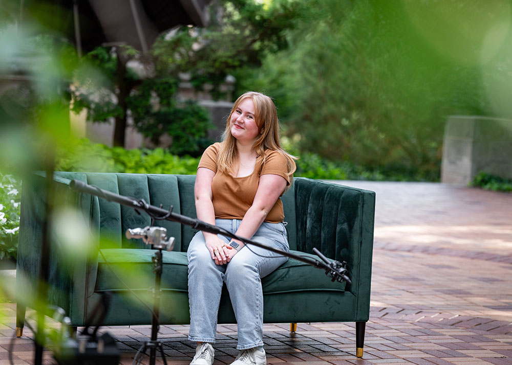 Person sitting on green couch with microphone in foreground