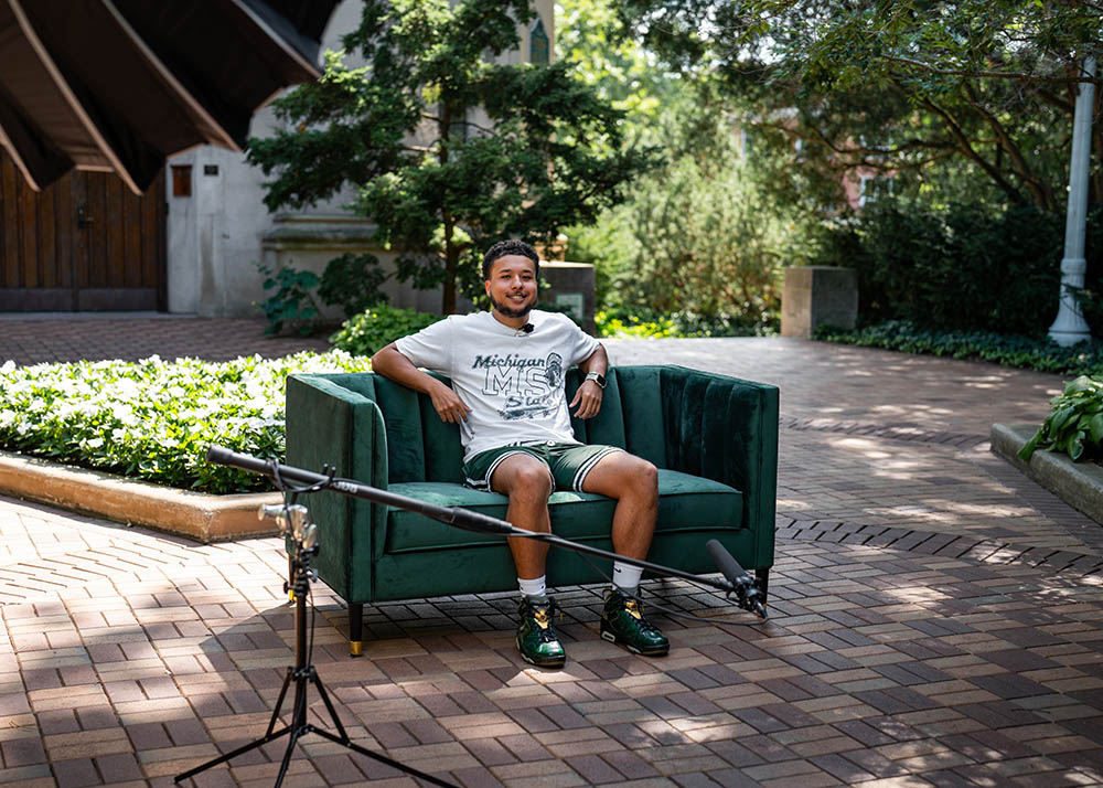 Person sitting on green couch with microphone in foreground