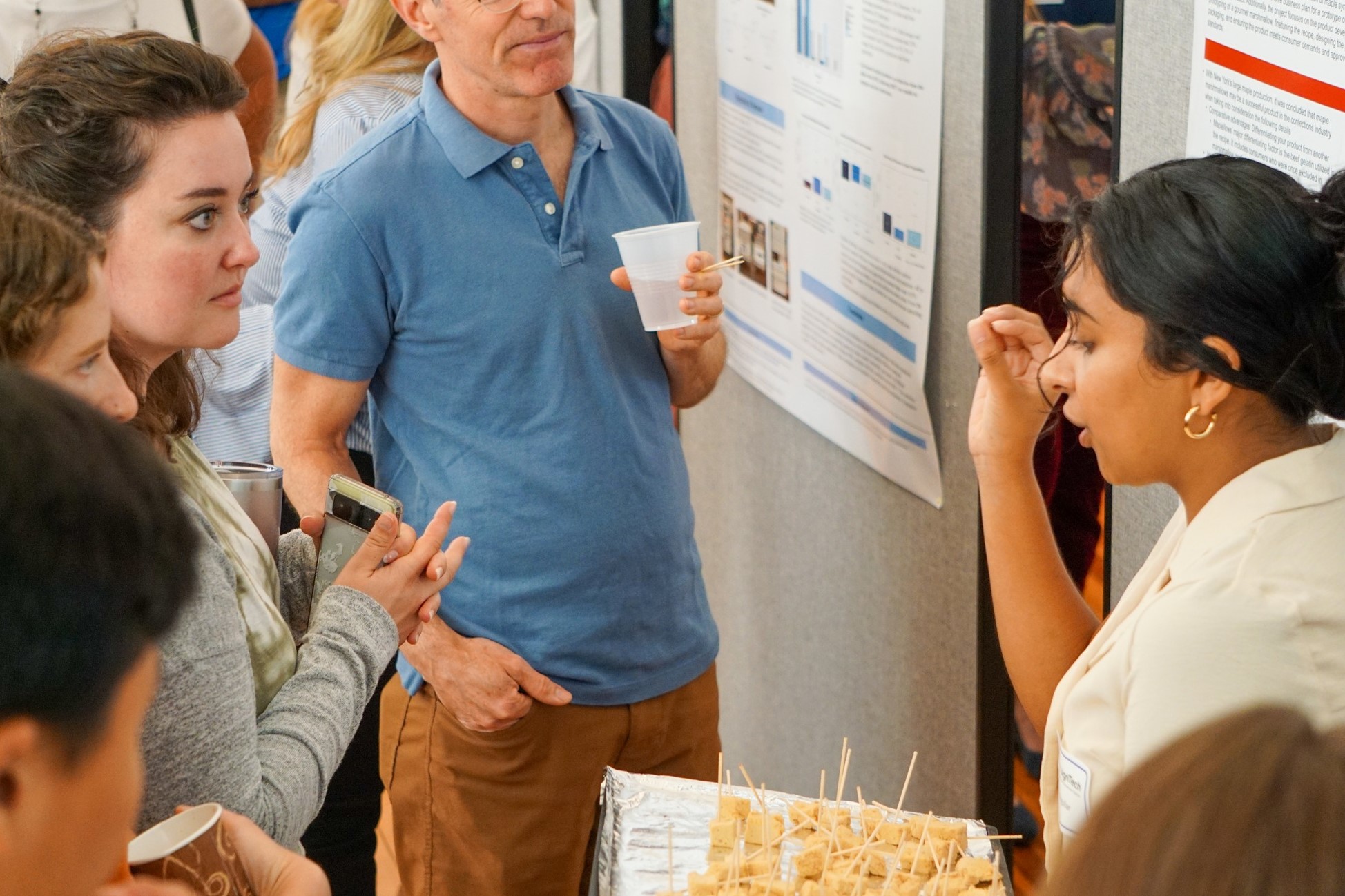 Anel Aguilar holds a plate of food at a poster sessions and speaks to a group of people around her