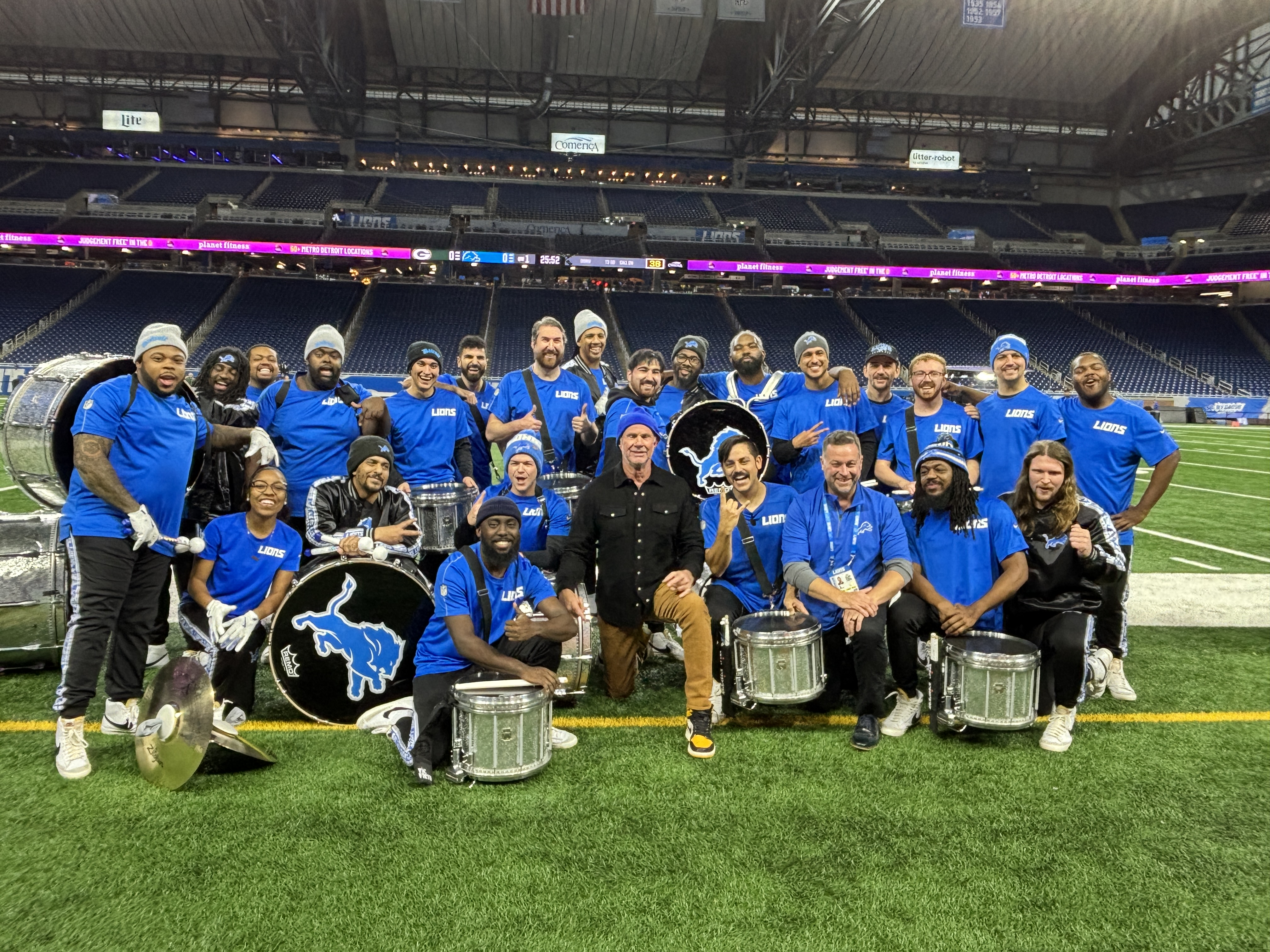 Several individuals holding musical instruments pose together on a football field.