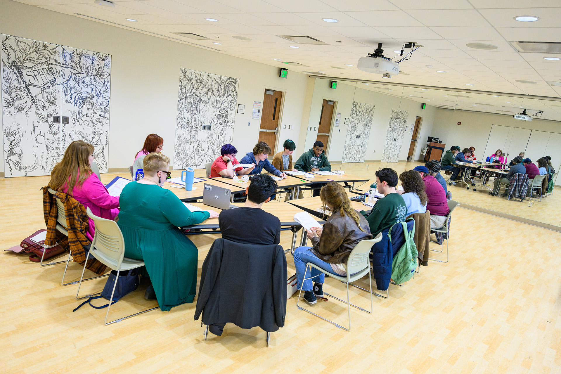 participants sitting around a table in a room with a mirror on one end