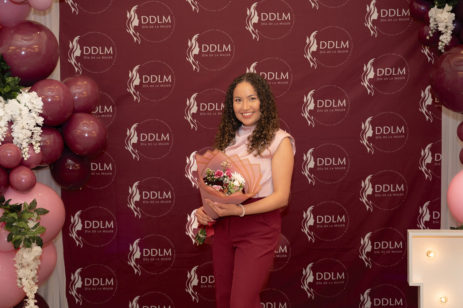 student holds a bouquet in front of backdrop